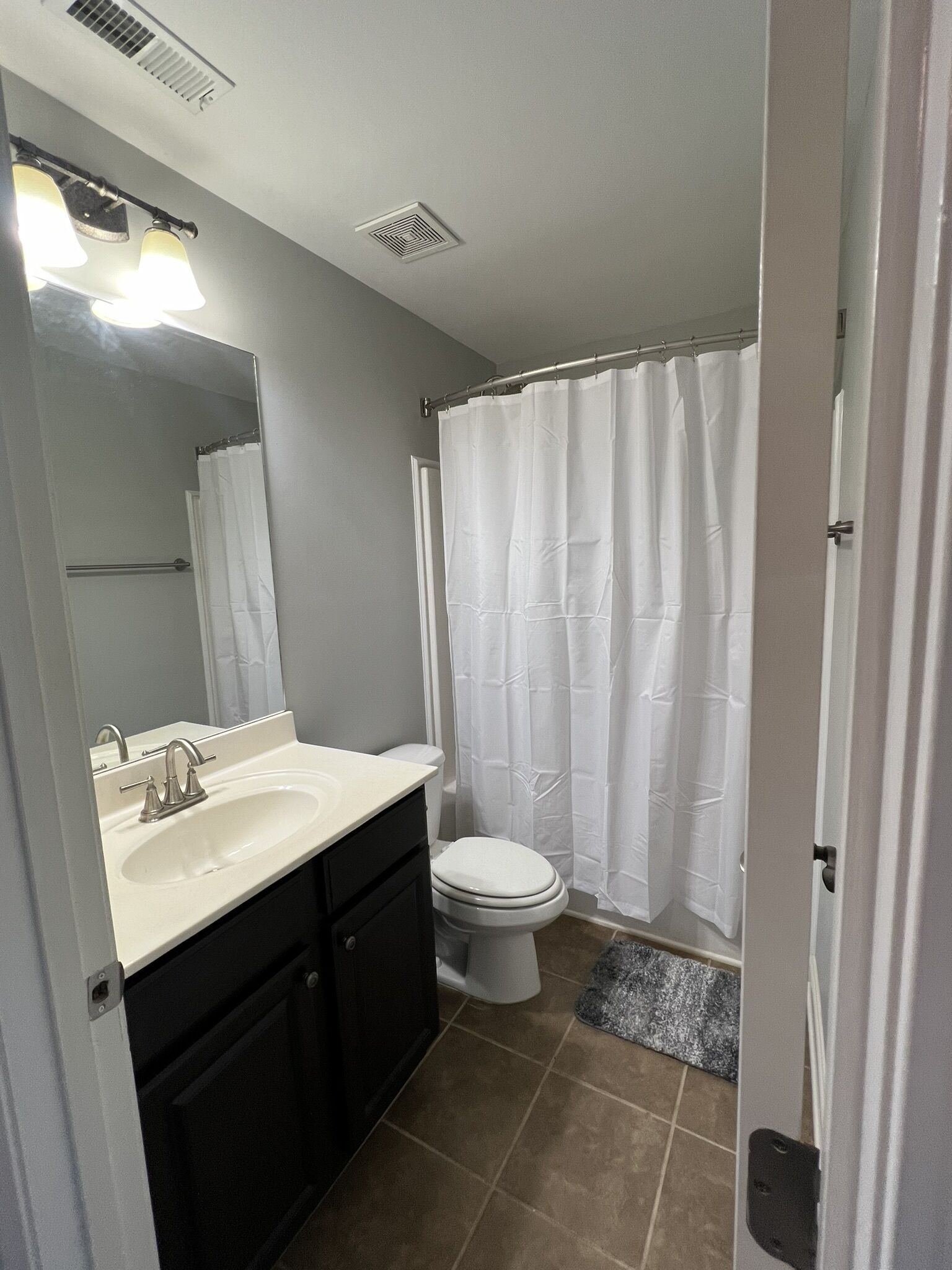 Une salle de bain équipée d’un lavabo, d’un miroir, de toilettes et d’un rideau de douche.