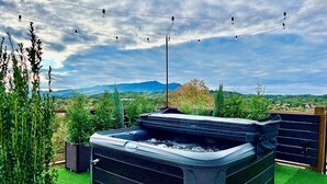 Un bain à remous sur un toit-terrasse, avec vue sur les montagnes et la verdure.