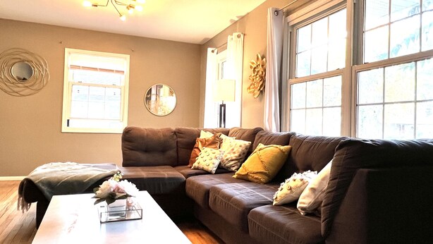 A living room with a brown sectional sofa, a white coffee table, and a mirror on the wall.