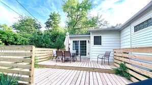 A wooden deck with a table and chairs, a small shed, and a wooden fence.