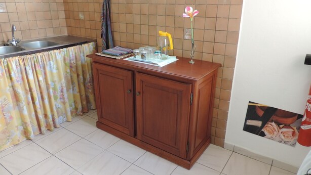 Una cocina con un armario de madera, un lavamanos y una cortina con estampado floral.