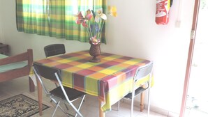 Un comedor con una mesa cubierta por un mantel colorido de cuadros, un jarrón con flores y una silla.