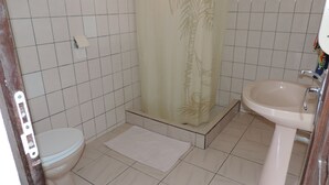 Un baño con inodoro, lavamanos y ducha con cortina estampada.