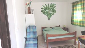 Un dormitorio con cama, una silla, una mesita de noche, una lámpara y un adorno en la pared.