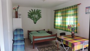 Una habitación pequeña y ordenada con una cama, una silla, una mesa y una planta en la pared.