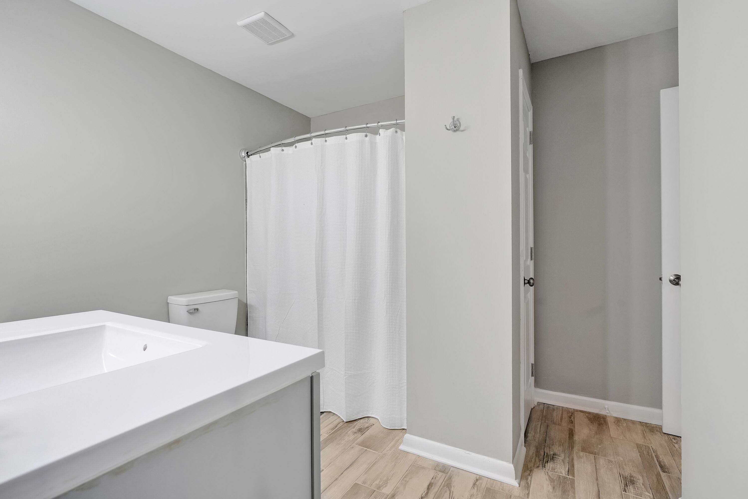 A bathroom with a white sink, toilet, and shower curtain.