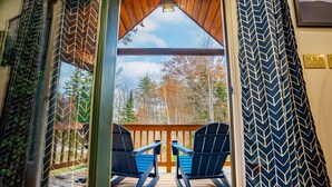 A wooden deck with two Adirondack chairs and a view of trees. - Sleeps 20 | Hot Tub | Game Room | Fire Pit |4500SF (Newry)