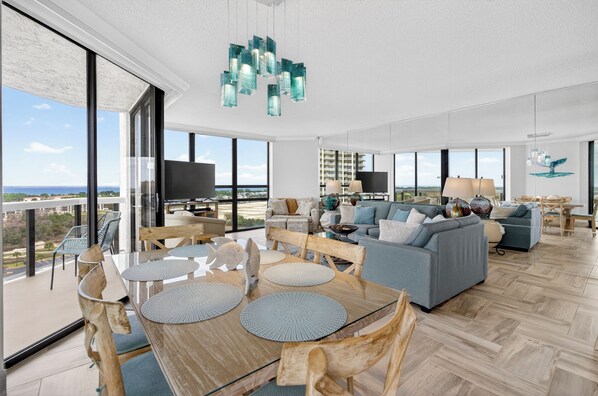 Un vaste espace de vie comprenant une grande table à manger, des canapés et un balcon offrant une vue sur la ville.
