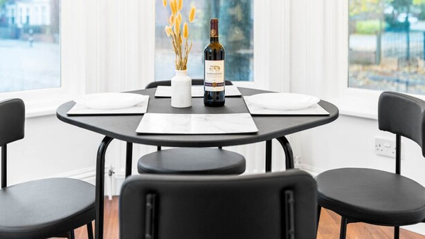 A dining table with a bottle of wine, white plates, and a vase with dried flowers. - Luxury Apartment - Wolverhampton (Wolverhampton)