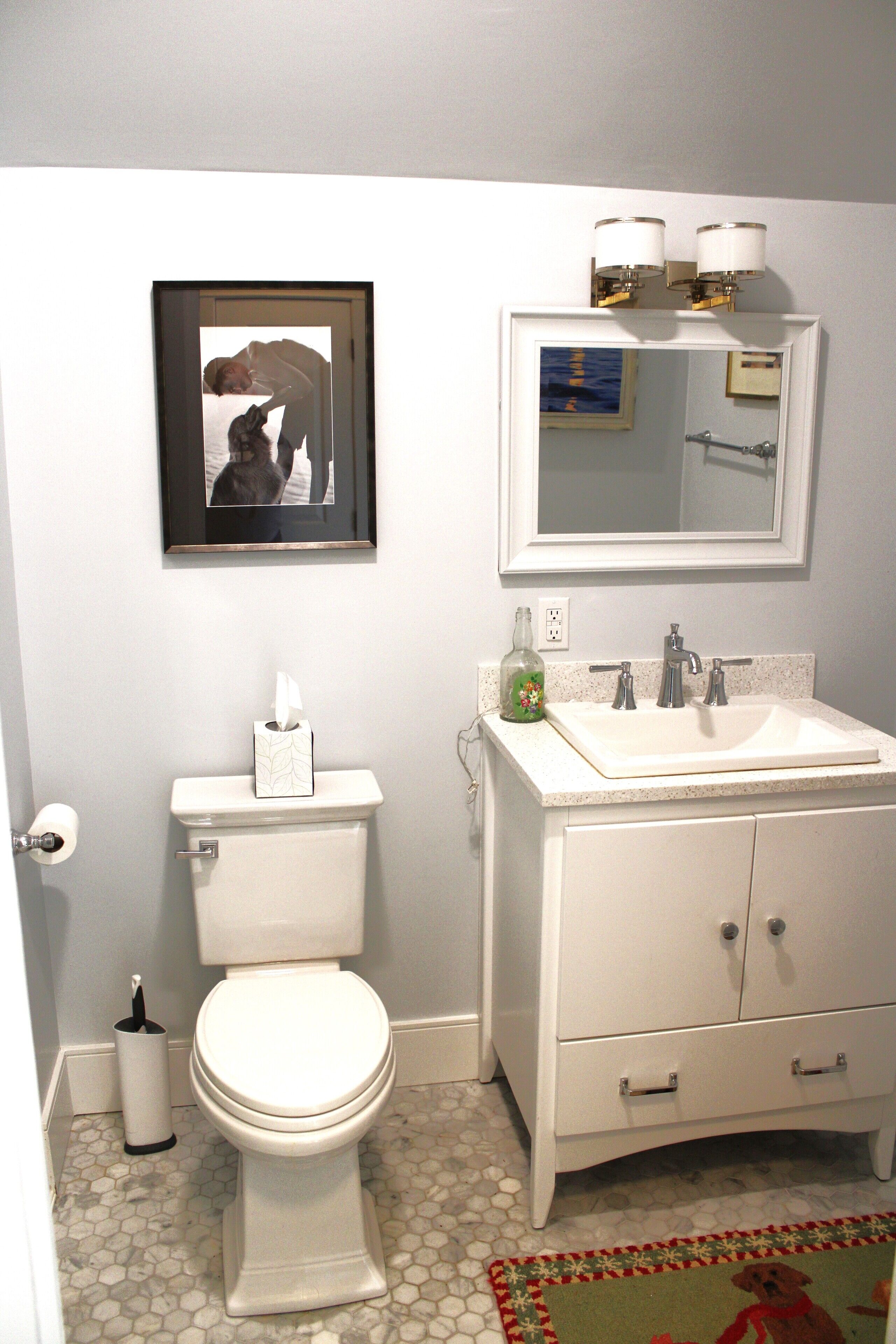 A bathroom with a toilet, sink, and mirror.