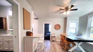 A modern kitchen with white cabinets, a wooden dining table, and a ceiling fan. - Beautifully remodeled single story cottage close to downtown Cincinnati! (Dayton)
