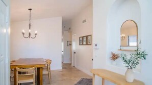 A dining area with a wooden table and chairs, a chandelier, and a mirror on the wall. - Perfectly-Located, Charming Family Home w/ Pool (Phoenix)