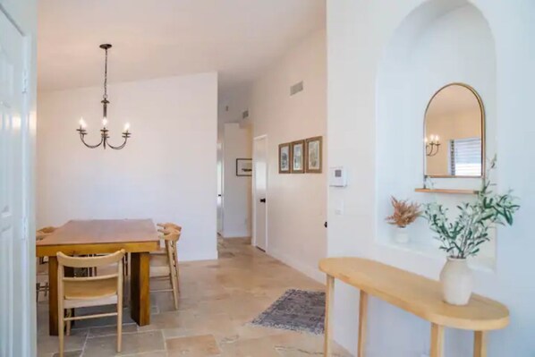 A dining area with a wooden table and chairs, a chandelier, and a mirror on the wall. - Perfectly-Located, Charming Family Home w/ Pool (Phoenix)