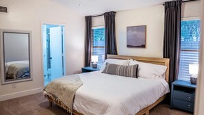 A bedroom with a large bed, two bedside tables, a mirror, and a window with curtains. - Perfectly-Located, Charming Family Home w/ Pool (Phoenix)