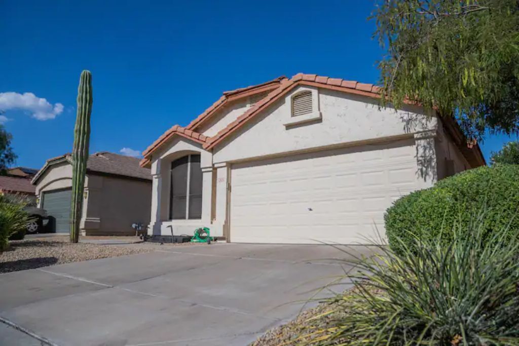 A single-story house with a garage, a tall cactus in the front yard, and a well-maintained lawn.