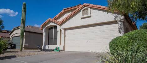 A single-story house with a garage, a tall cactus in the front yard, and a well-maintained lawn.