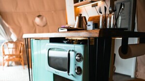 A compact kitchenette with a built-in stove, a small sink, and storage bins.