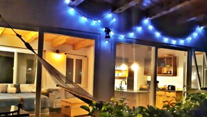 Un rincón al aire libre acogedor con una hamaca, una mesa de comedor y sillas.