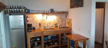 Una cocina compacta con refrigerador, armarios de madera, un lavamanos y una pequeña mesa.