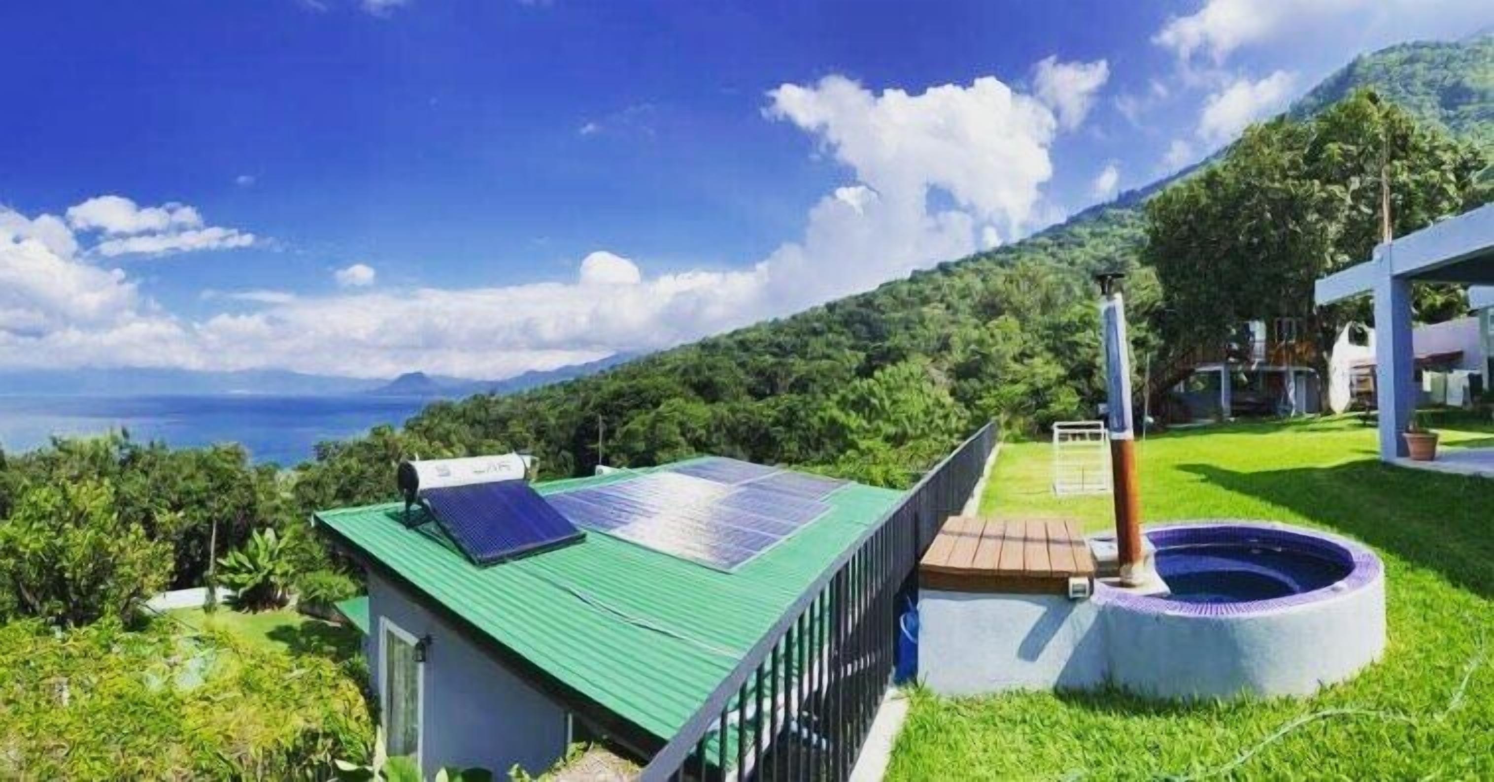 Un edificio moderno con techo verde, paneles solares y piscina.