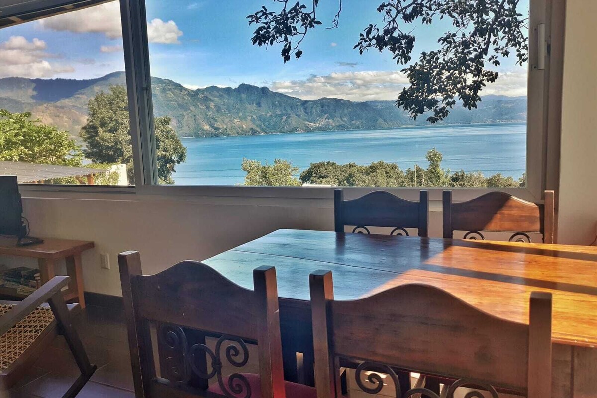 A dining area with a view of a lake and mountains.