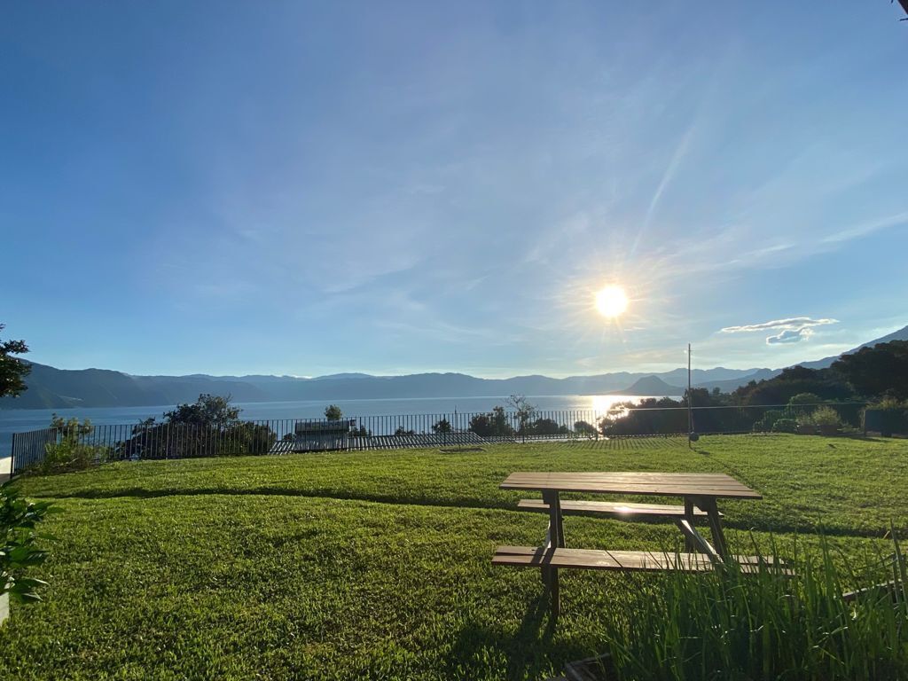 Een picknicktafel in een grasveld, met uitzicht op een meer en bergen op de achtergrond.