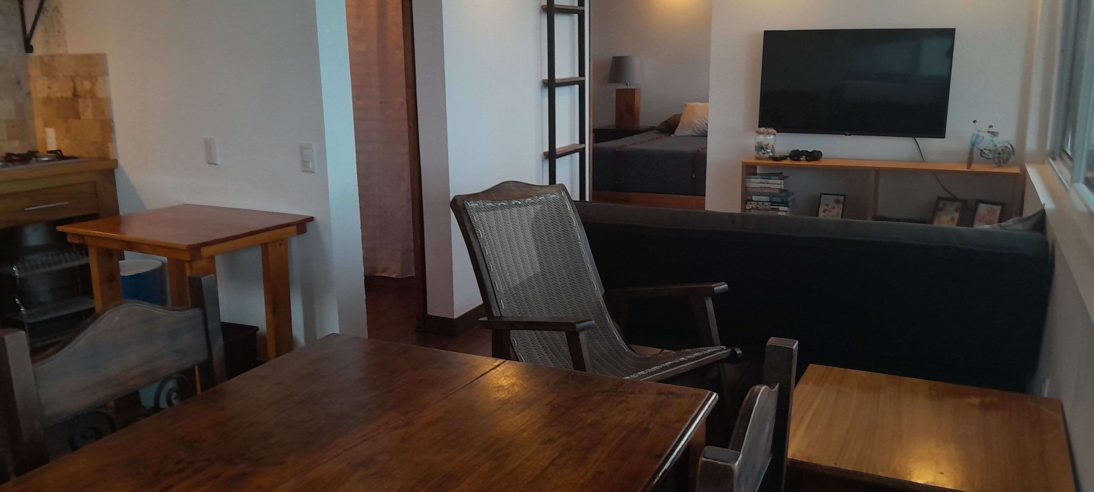 A compact living space with a dining area, a bed, a TV, and a bookshelf.
