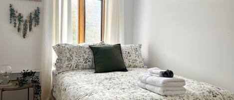 A bedroom with a bed, a bedside table, and a window.