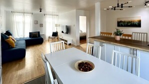 A modern living space with a dining area, a sofa set, a TV, and a painting on the wall. - Large Apartment in Downtown (Québec)