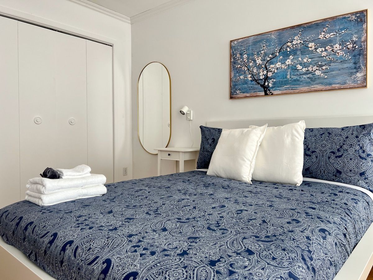 Ein Schlafzimmer mit einem Bett, einem Nachttisch, einem Spiegel und einem Bild an der Wand.