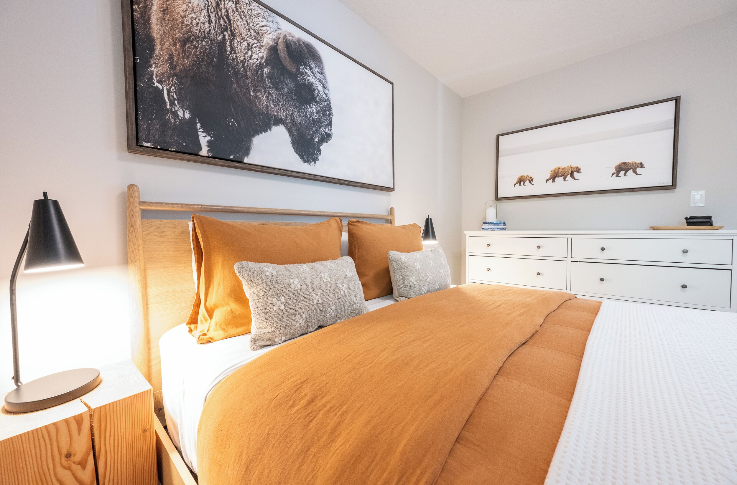 Een slaapkamer met een groot bed, een houten hoofdeinde en een nachtkastje met een lamp.