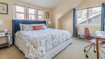 A bedroom with a large bed, a desk, and a chair.
