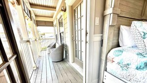 A cozy room with a bed, a chair, and a wooden porch.