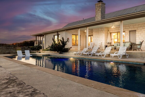 A poolside area with lounge chairs and a stone building with a chimney.