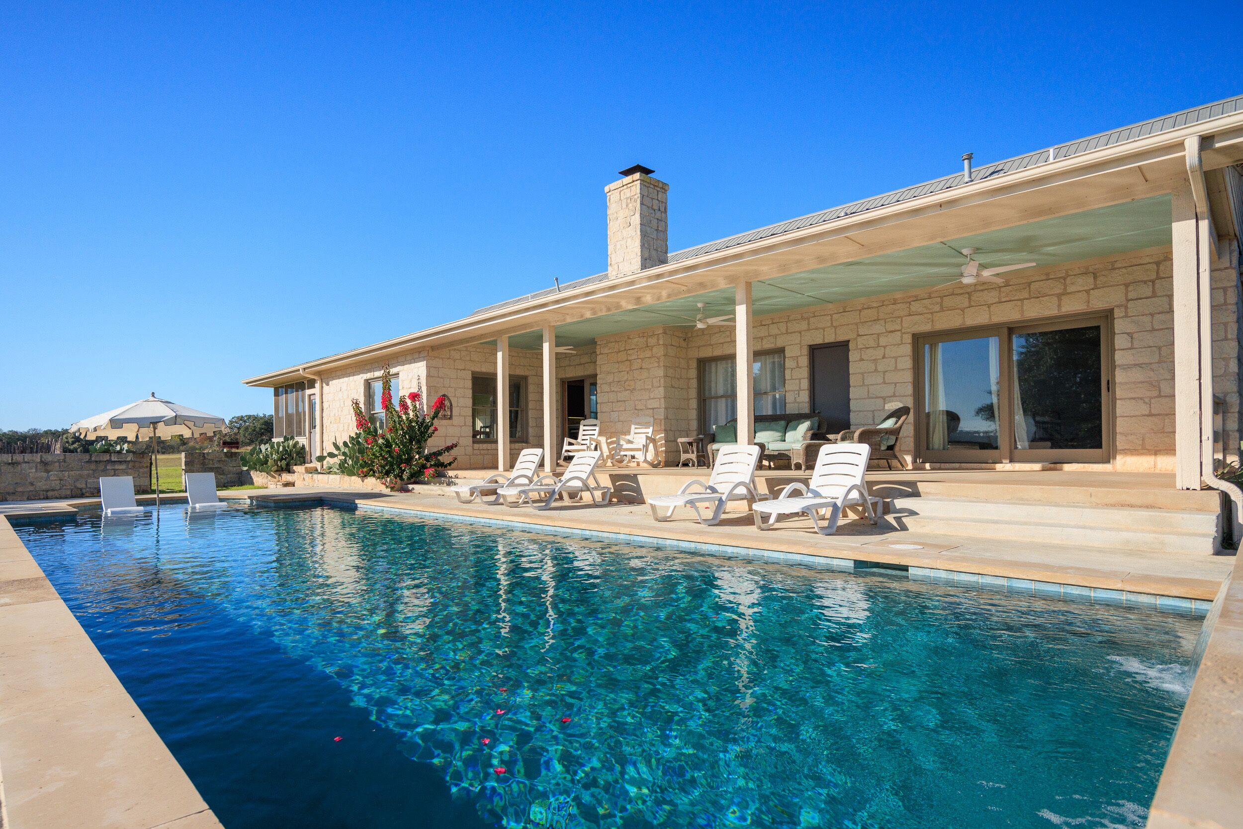 A swimming pool with lounge chairs and a covered patio area.