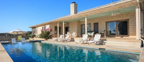 A swimming pool with lounge chairs and a covered patio area.
