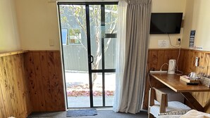 Une chambre d’hôtel avec deux lits, un bureau avec une bouilloire, une télévision et une vue sur l’extérieur.
