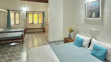 A bedroom with a large bed, a smaller bed, a ceiling fan, a window with curtains, and a wall-mounted light fixture.