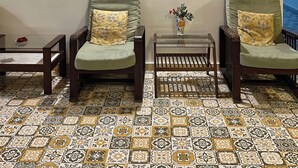 Una sala de estar con dos sillones, una mesita y estantes decorativos con cerámica.