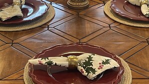 Een eettafel met een bloemstuk in het midden en een kandelaar.