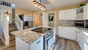 Une cuisine moderne avec des meubles blancs, une cuisinière encastrée et un grand îlot central.