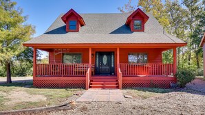 Une maison rouge à deux étages, dotée d’un porche, d’une porte d’entrée et d’une petite fenêtre au deuxième étage.