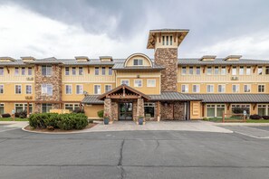 A multi-story hotel with a stone facade, a central entrance with a covered porch, and a parking lot in front. - Desert Canyon Golf Resort (Orondo)