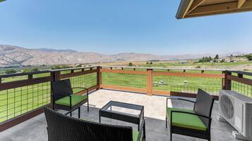 Un balcón con mobiliario de mimbre y vistas a un campo de golf y montañas.