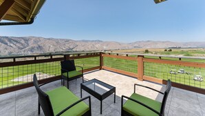 A balcony with a view of mountains, a table, and green cushioned chairs. - Desert Canyon Golf Resort (Orondo)