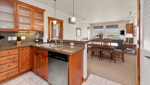 A modern kitchen with granite countertops, wooden cabinets, a dishwasher, and a dining area with a table and chairs. - Desert Canyon Golf Resort (Orondo)