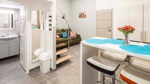 A modern bathroom with a sink, toilet, and shower area. There is a staircase leading to a bedroom with a bed and a nightstand. - X - Bella Apartment II Budapest (Budapest)