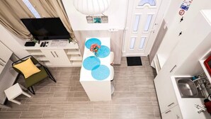 A compact kitchen with a white countertop, a sink, and a dining area with a table and chairs. - X - Bella Apartment II Budapest (Budapest)