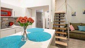 A modern kitchen with white cabinets, a red microwave, and a blue rug. - X - Bella Apartment II Budapest (Budapest)
