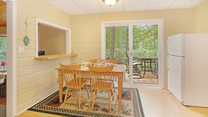 A small, cozy kitchen with a dining area, wooden furniture, and a view through the glass door. - Quiet Cabin Setting on small river
 (Chase)
